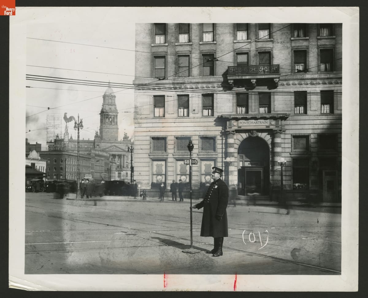 Traffic police officer operating a manually controlled STOP sign at a Detroit intersection around 1920.